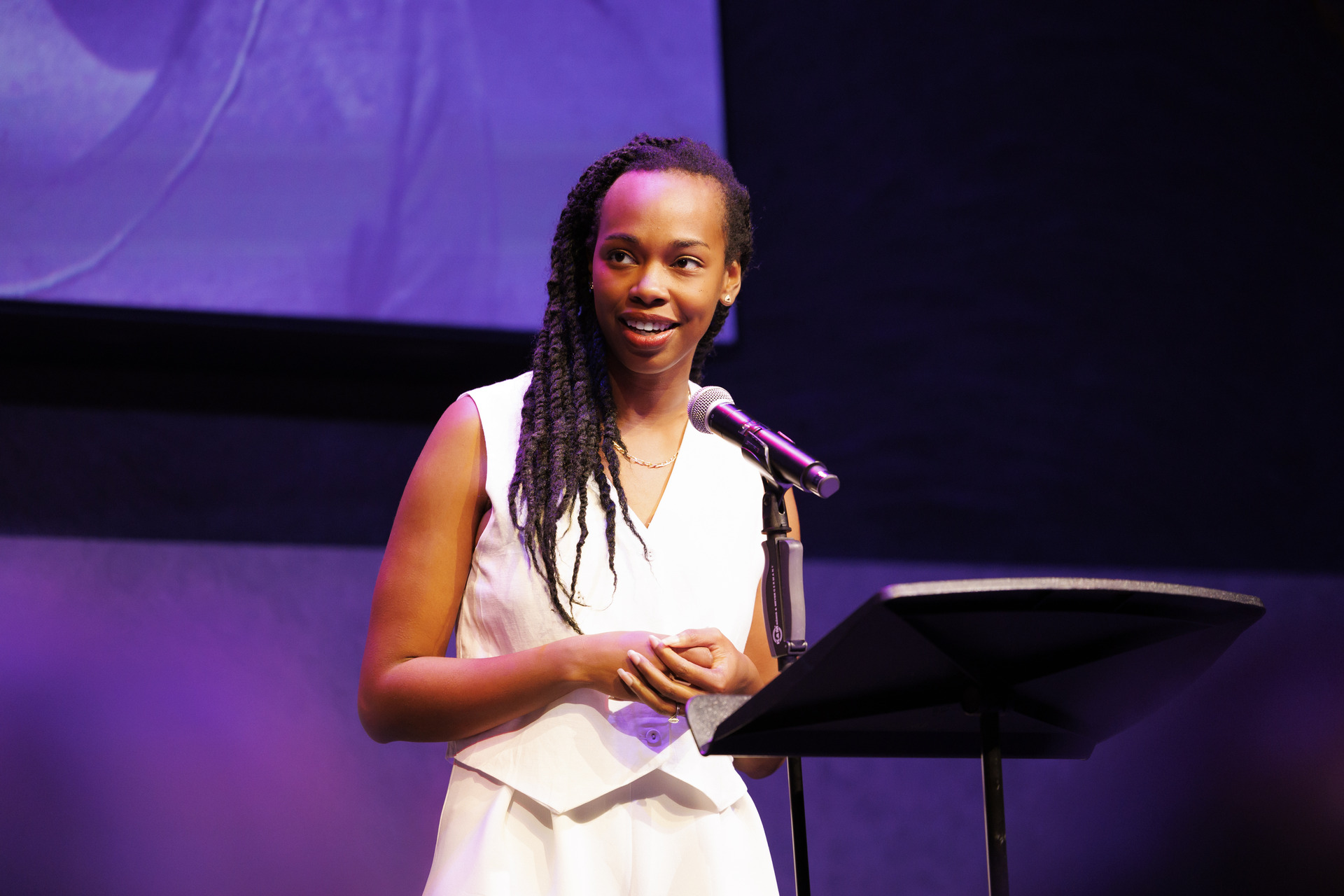 Fedna Jacquet speaking at a lectern during Myths: The People Who Carry The Sky
